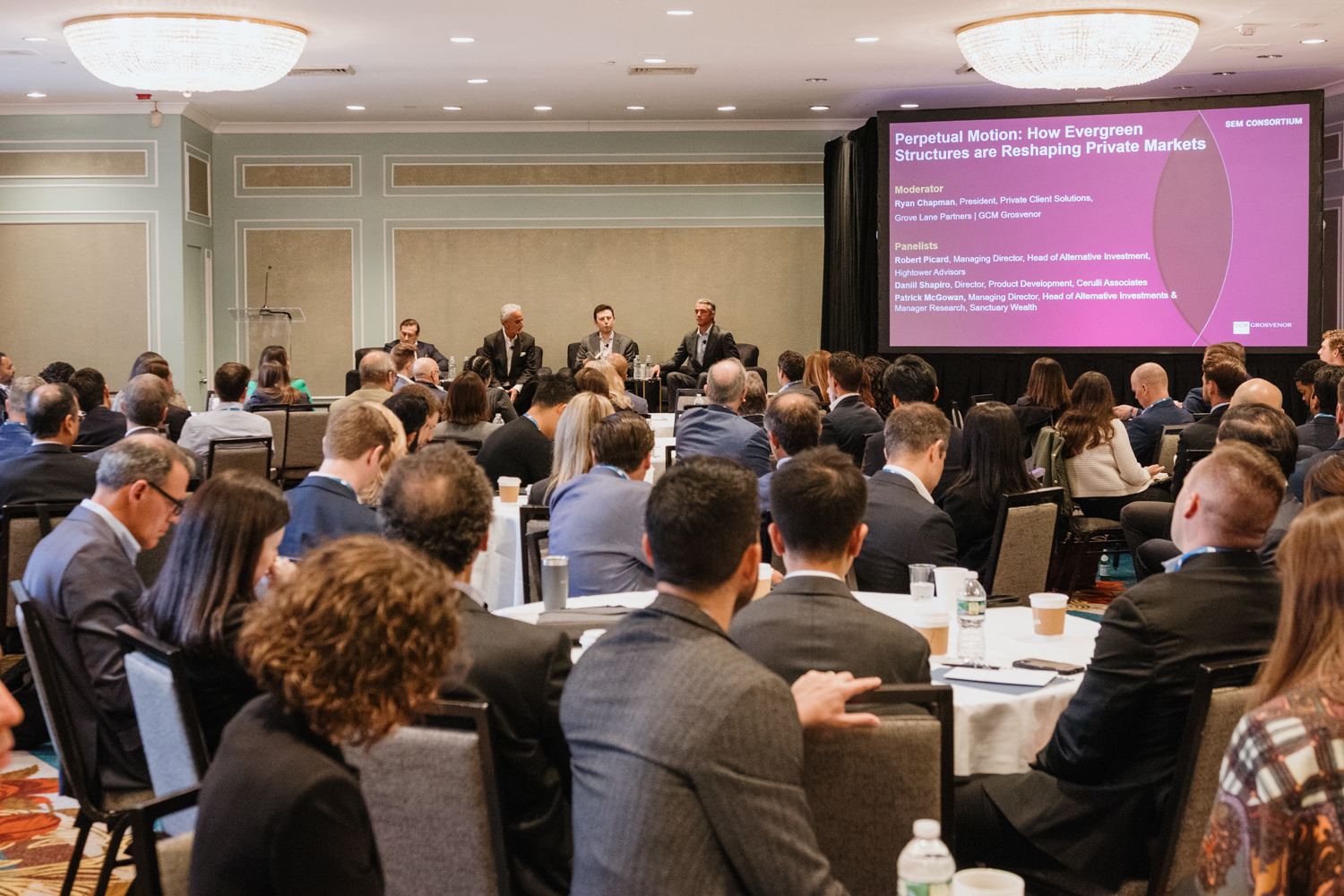 Crowded meeting room at SEM Consortium 2025 with panelists on stage